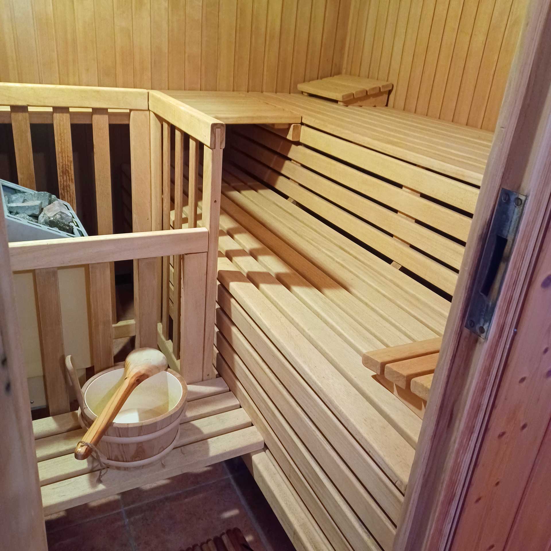 Innenansicht der Sauna mit schönen Brettern, einem Ofen und ein Fass für Aufgüsse