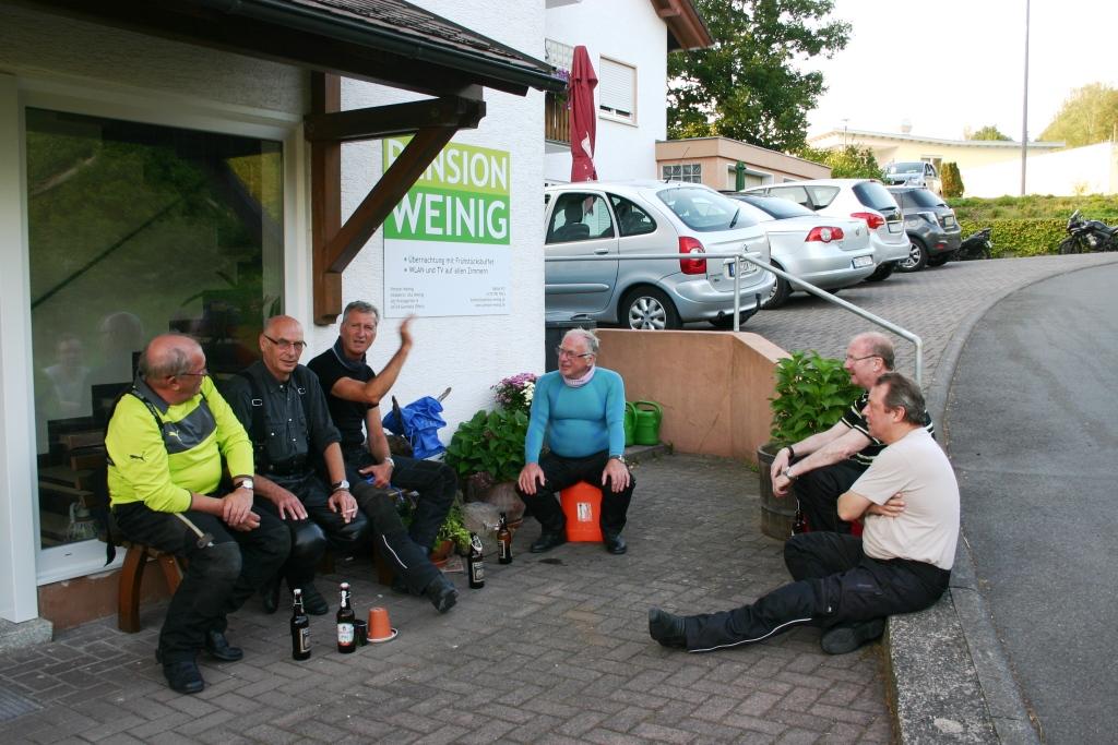 Motorradfahrer sitzen vor der Pension Weinig und trinken Bier