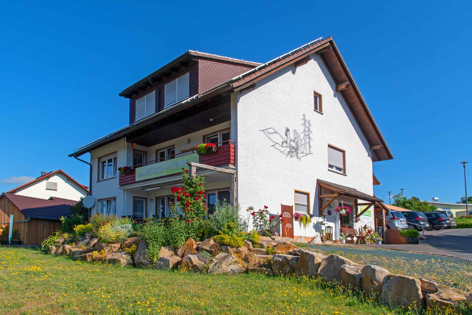 Das Foto zeigt die Seminarpension Weinig mit Garten und Parkplatz