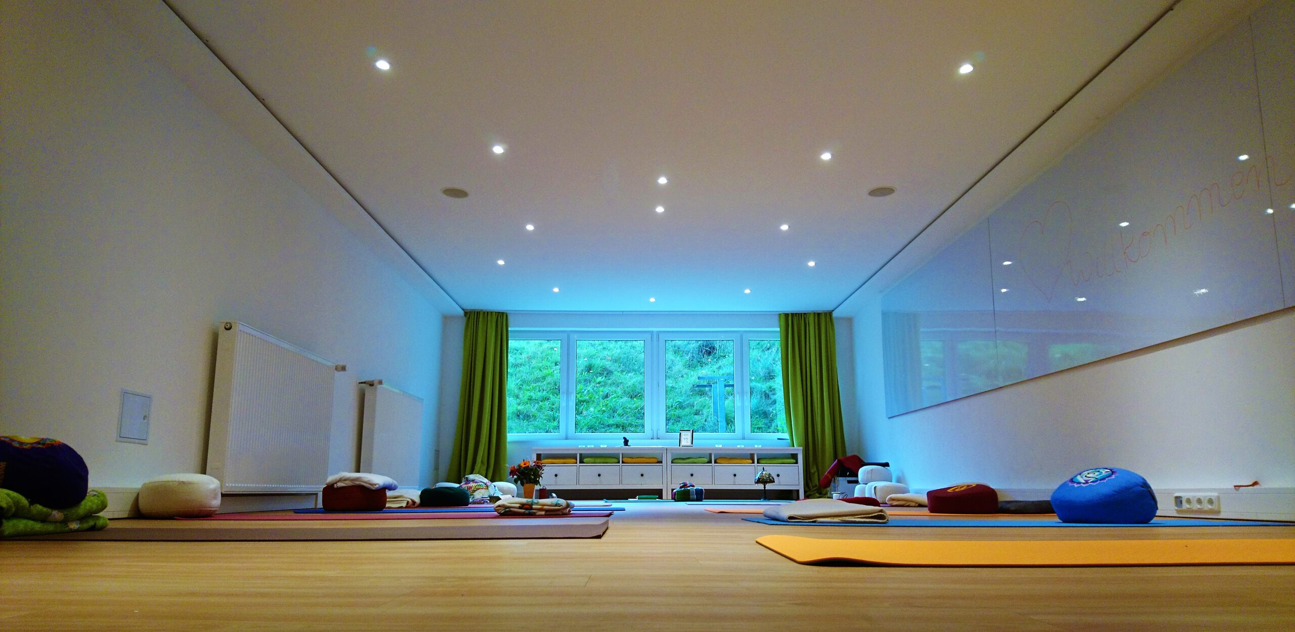 Yogamatten liegen in einem wunderschönen Seminarraum. Im Hintergrund ist ein schönes, blaues Licht.