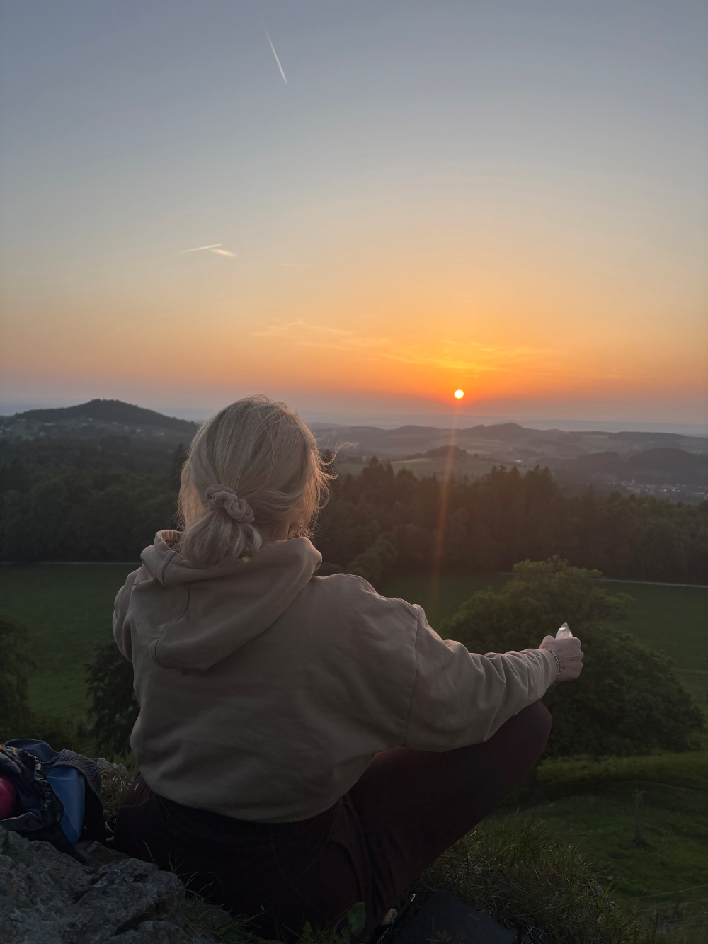 Blonde Frau im Schneidersitz vor sem Sonnenauuntergang am Wachrküppel